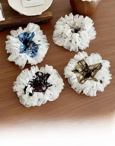 Flat lay view of four floral lace scrunchies in blue, beige, black, and green colors