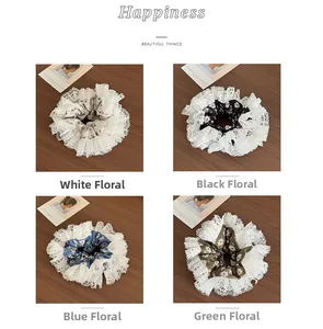 Detail of four floral lace scrunchies in white, black, blue, and green on wood