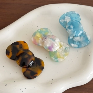 Trois barrettes en acétate aux motifs écaille et marbre sur une assiette blanche