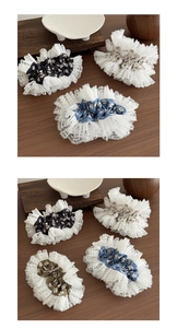 Close-up of lace-trimmed floral scrunchies in various vintage colors on a wood surface