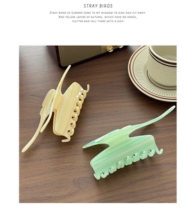 Detail view of large acetate butterfly hair claws in cream yellow and mint green