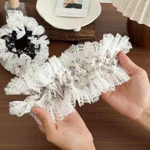 Floral lace hair scrunchies with white and black patterns in a warm lifestyle setting