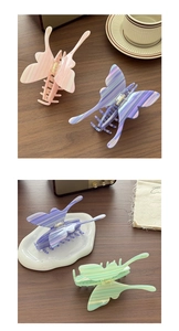 Detailed close-up of three acetate butterfly hair claws with marble texture on wood surface
