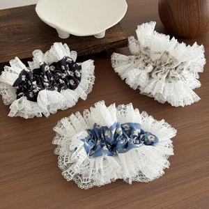 Floral lace hair scrunchies in black, cream, and blue displayed on a wooden surface