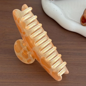 Pince à cheveux vintage orange à motif vache pour coiffage sur surface en bois