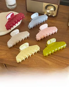 Detail view of six colorful acetate shark hair clips with rhinestones on a wooden desk