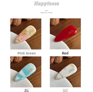 Detail of 4mm thick acetate hair clips with marble patterns and gold Barrette lettering