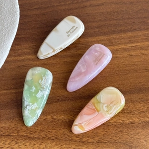 Set of four 4mm thick acetate hair clips with marble texture on dark wood surface