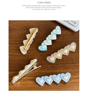 Détail de cinq barrettes à cheveux en forme de cœur coloré sur fond en bois