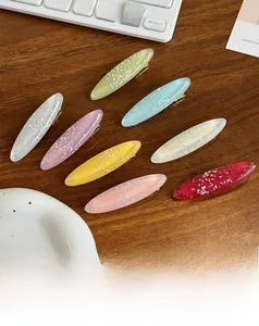 Detailansicht von 8 bunten glitzernden Acetat-Haarspangen auf einer Holzfläche
