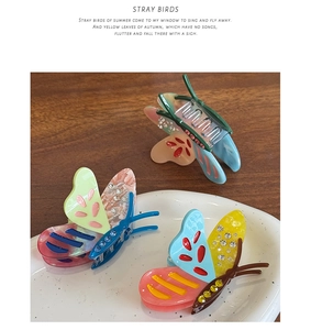 Detail of acetate butterfly hair clips with rhinestone accents on a wooden desk