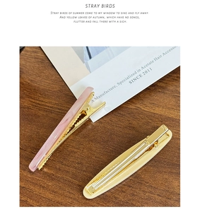 Close-up of pink marble and cream acetate hair clips on a wooden surface
