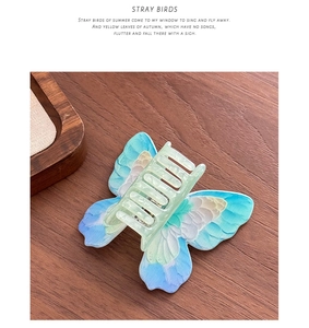 Detailed macro view of the translucent butterfly hair claw clip with blue-green gradient wings