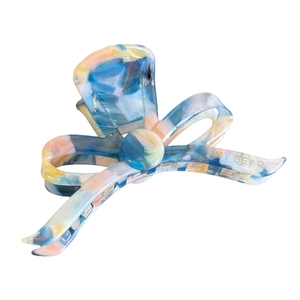 Elegant bow-shaped hair claw clip with colorful marble acetate texture and golden logo