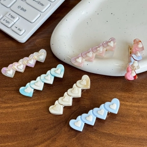 Barrettes à cheveux en acétate en forme de cœur rose et bleu sur une table en bois