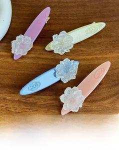 Detail of four colorful acetate camellia flower hair clips on a dark wood surface