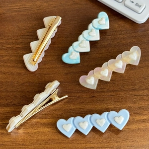 Lot de cinq pinces à cheveux en forme de cœur couleurs bonbon sur bois foncé