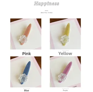 Detail showing four acetate camellia hair clips in pink yellow blue and purple