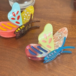 Elegant acetate butterfly hair clips with rhinestones on a warm wooden background