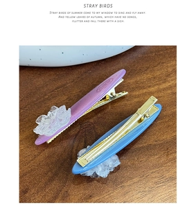 Close-up of purple and blue camellia acetate hair clips with golden metal base detail