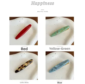 Detailed macro view of four colors of marbled acrylic hair clips with gold lettering