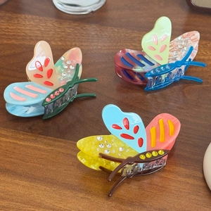 Three colorful acetate butterfly hair clips with sparkling rhinestones on wood
