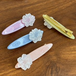 Elegant camellia acetate hair clips in pastel colors with glitter finish and gold duckbill base