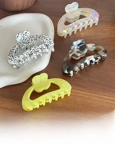 Detail view of four acetate floral hair claws in marble and cow prints with rhinestones