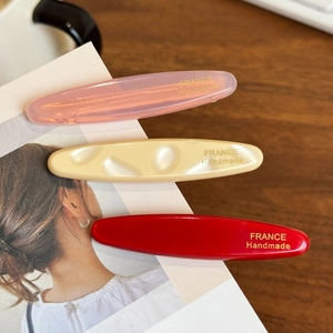 Three-piece oval acetate hair clip set in pink cream and red with gold emblem