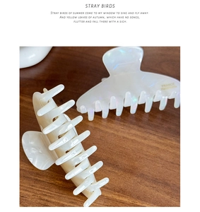 Detail of marble pattern and pearlescent acetate hair claws on a wooden table