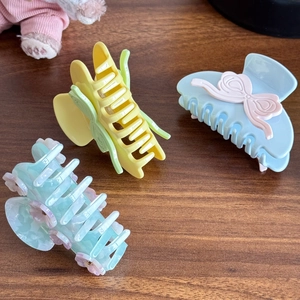 Tre eleganti pinze per capelli in acetato con farfalle e fiori su tavolo di legno