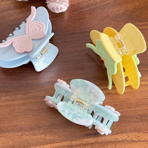 Eleganti fermagli per capelli a farfalla in colori macaron su sfondo di legno rustico