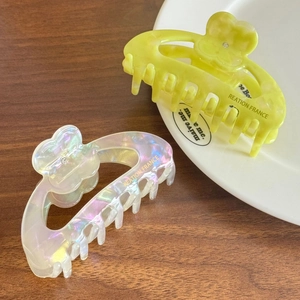 Floral acetate hair claw clip with rhinestones and polished finish on a wooden desk