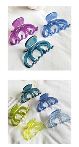 Macro shot of colorful translucent acetate hair claw clips on white fabric with books