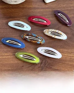 Lot de 8 barrettes ovales en acétate de diverses couleurs sur fond en bois sombre