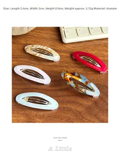 Vue détaillée de barrettes ovales en acétate en cinq couleurs sur une table en bois