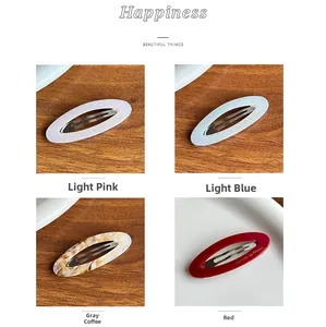 Détail macro de barrettes ovales en acétate en quatre couleurs avec logo doré gravé