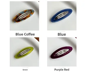 Gros plan de quatre barrettes en acétate coloré sur un plateau avec détails dorés