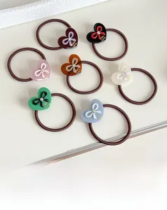 Macro detail of acetate heart hair ties with golden bow print and small crystal center