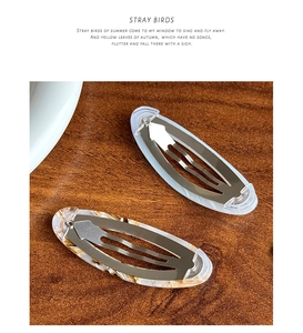 Détail de barrettes BB en acétate motif marbre avec étiquette dorée sur fond en bois