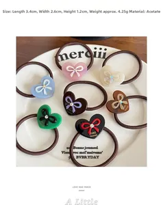 Close-up of heart-shaped acetate hair ties with bow detail and rhinestone in a tray