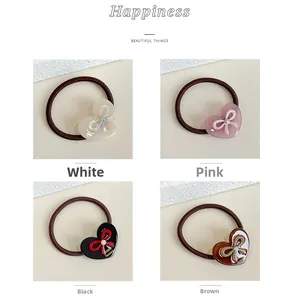 Detailed view of four acetate heart bow hair ties in white pink black and brown colors