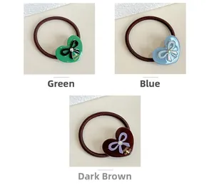 Close-up of heart resin hair ties in green, blue, and brown with gold bow details