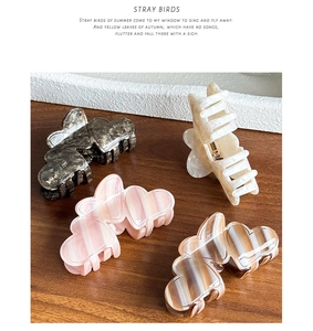 Detail view of heart-shaped acetate hair claws in four marble patterns on a wooden table