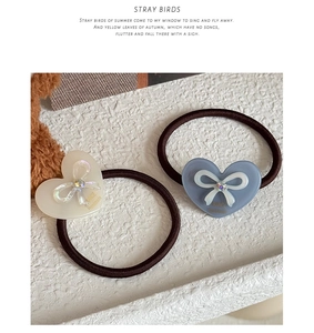 Detail view of heart hair ties with rhinestone bows and handmade golden logo lettering