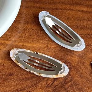 Barrettes BB ovales en acétate blanc crème et motif marbre sur une surface en bois brun