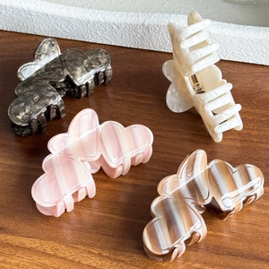 Elegant heart-shaped acetate hair claws in various striped and tortoiseshell patterns