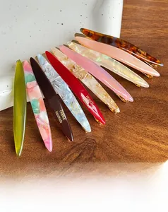 Variety of handmade acetate hair clips with tortoiseshell and marble patterns on a ceramic plate