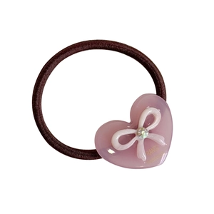Pink heart hair tie with white bow and crystal accent on brown elastic band