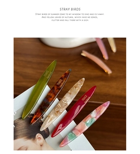 Close-up of elegant acetate hair clips in multiple colors with gold handmade text detail